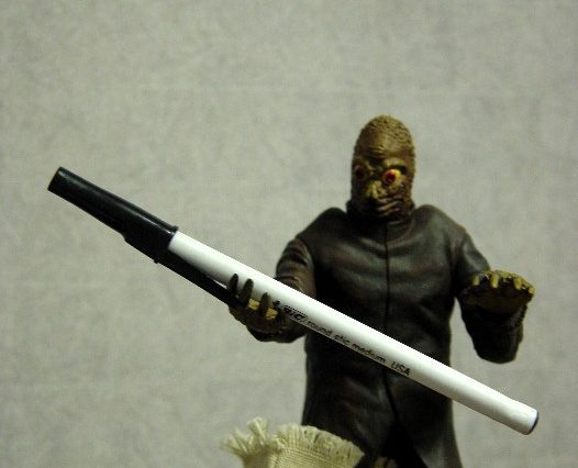 A mole man action figure holding a pen