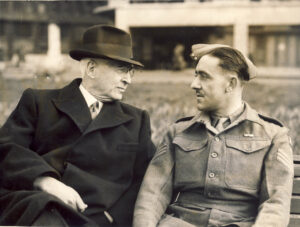 Baruch wearing overcoat and hat talking with soldier in uniform.